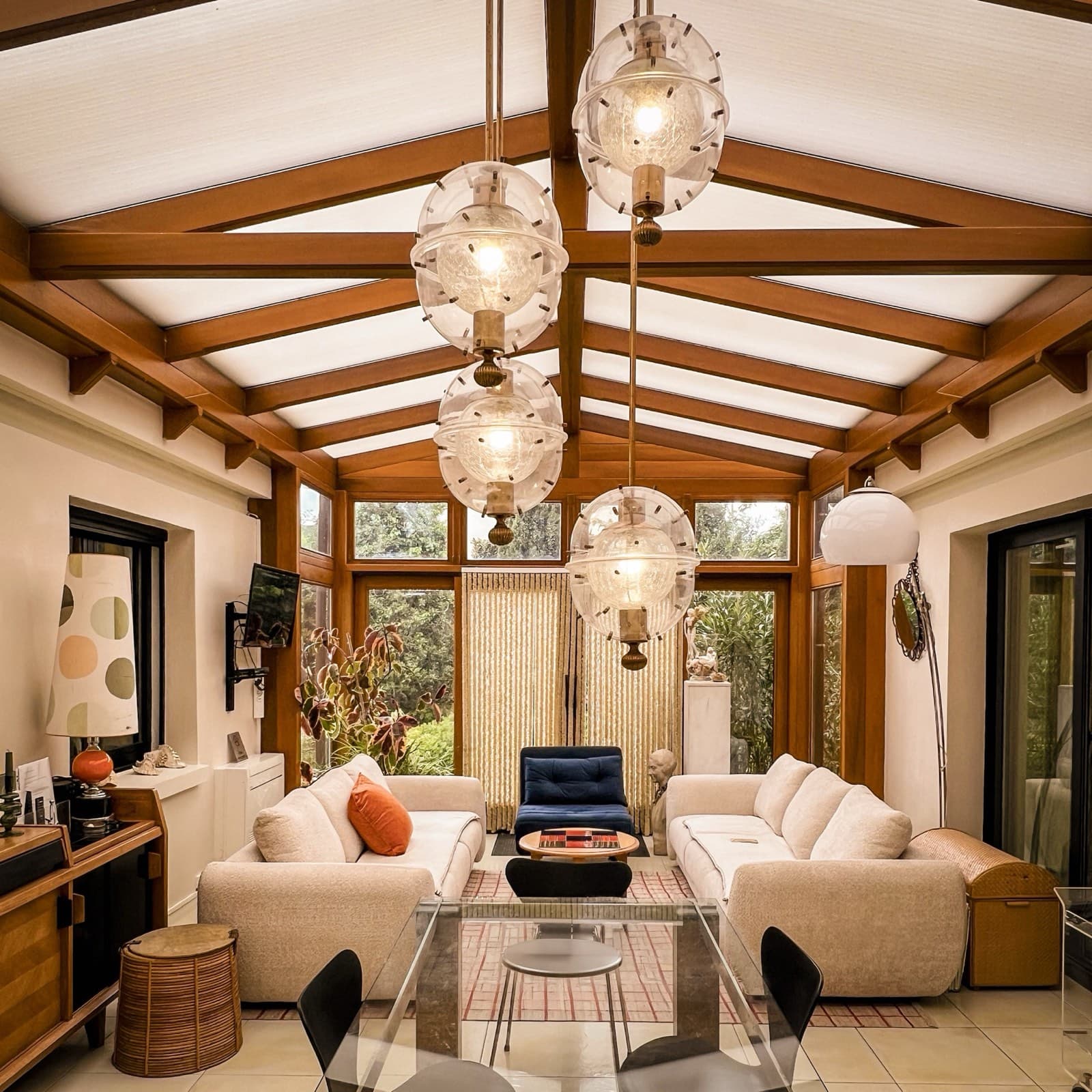 Salon chaleureux aux poutres en bois et grandes fenêtres, rénovation de maison à Coulommiers par Studio Songe